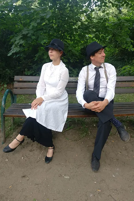 Zwei Schauspieler im Kostüm bei einer Stadtrally Krimi & Tour auf einer Bank.