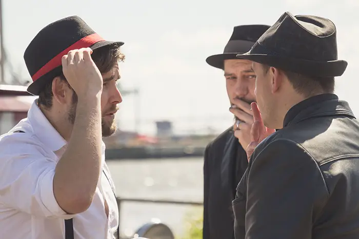 Drei als Mafiosi verkleidete Schauspieler bei einer Vorstellung in Hamburg